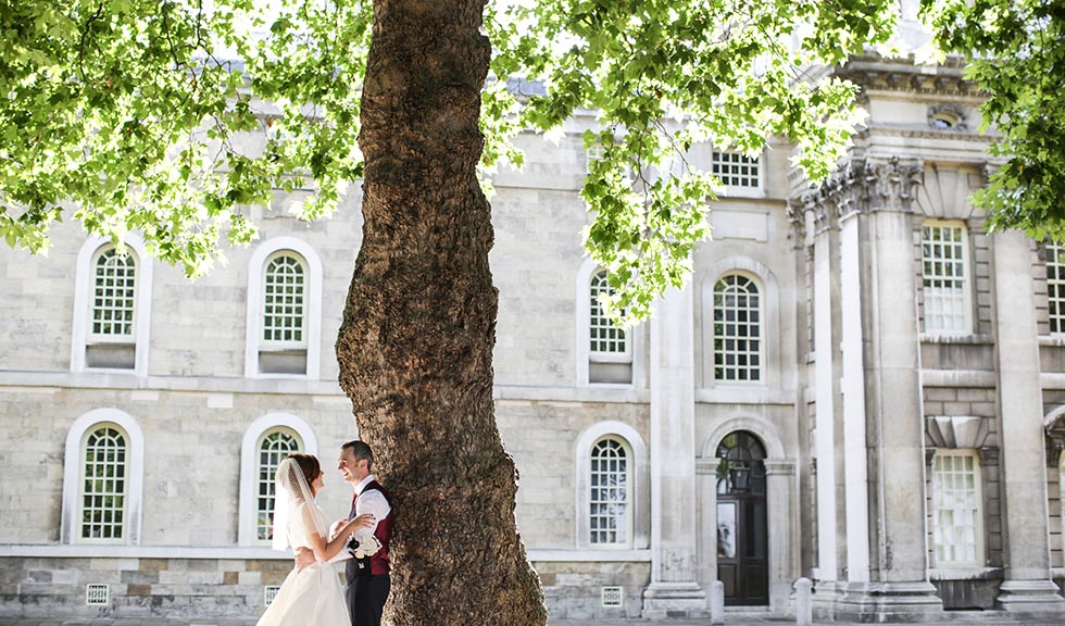Brighton and groom under a tree outside Greenwich Old Royal Naval College