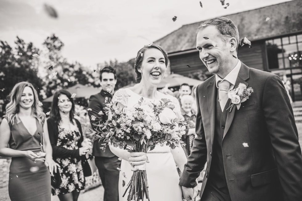 Black and White image of wedding couple after the confetti throwing