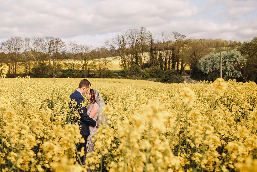 Bride and groom hug in the oil seed rape at Farbridge
