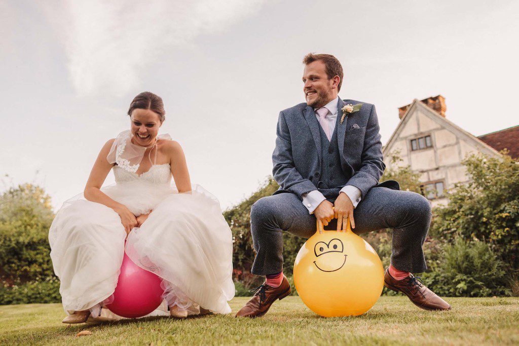 Bride and groom bounce on space hoppers at their Grittenham Barn wedding