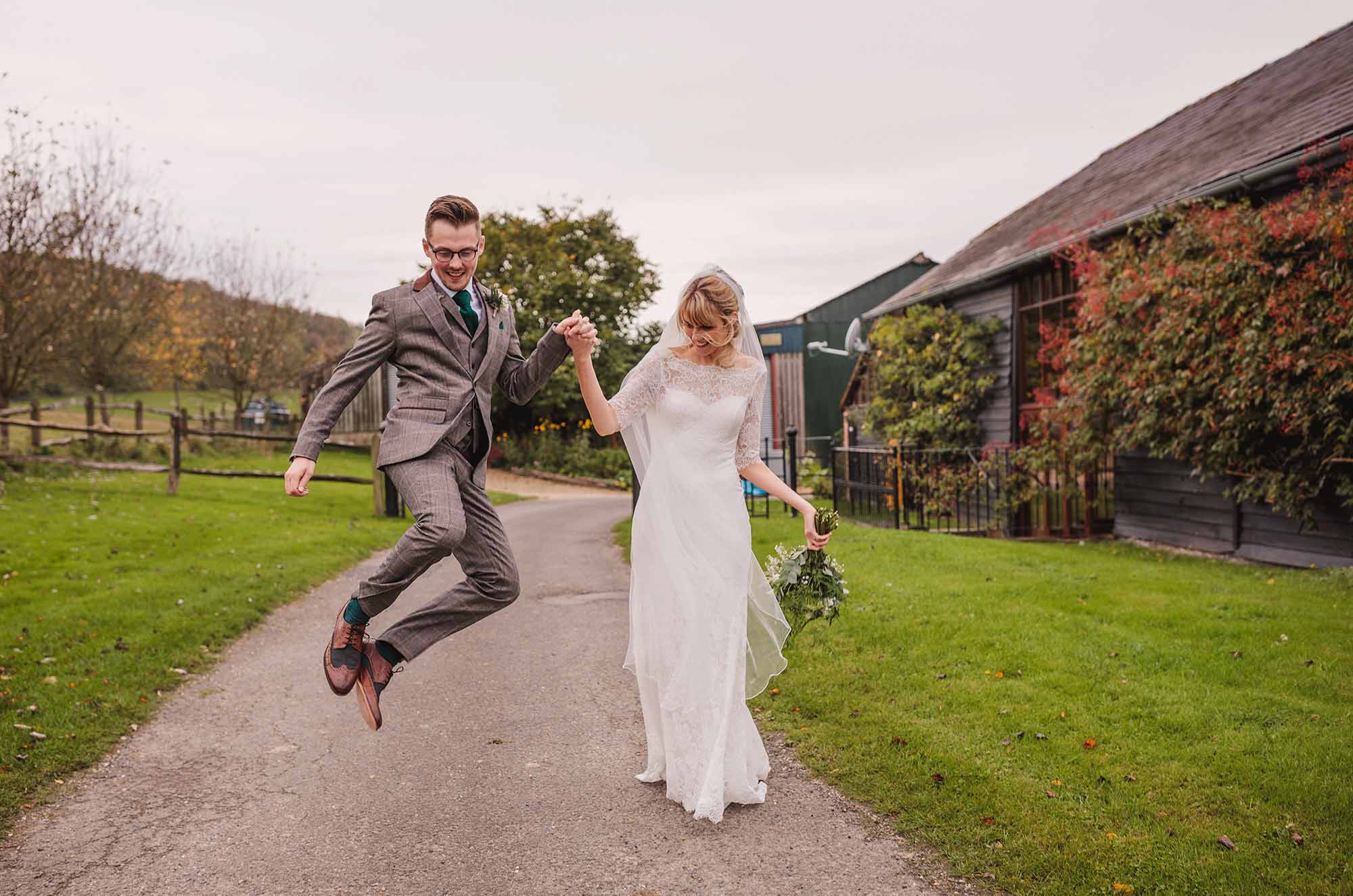 Groom jumping and clicking heals with bride at Uplwaltham Barns