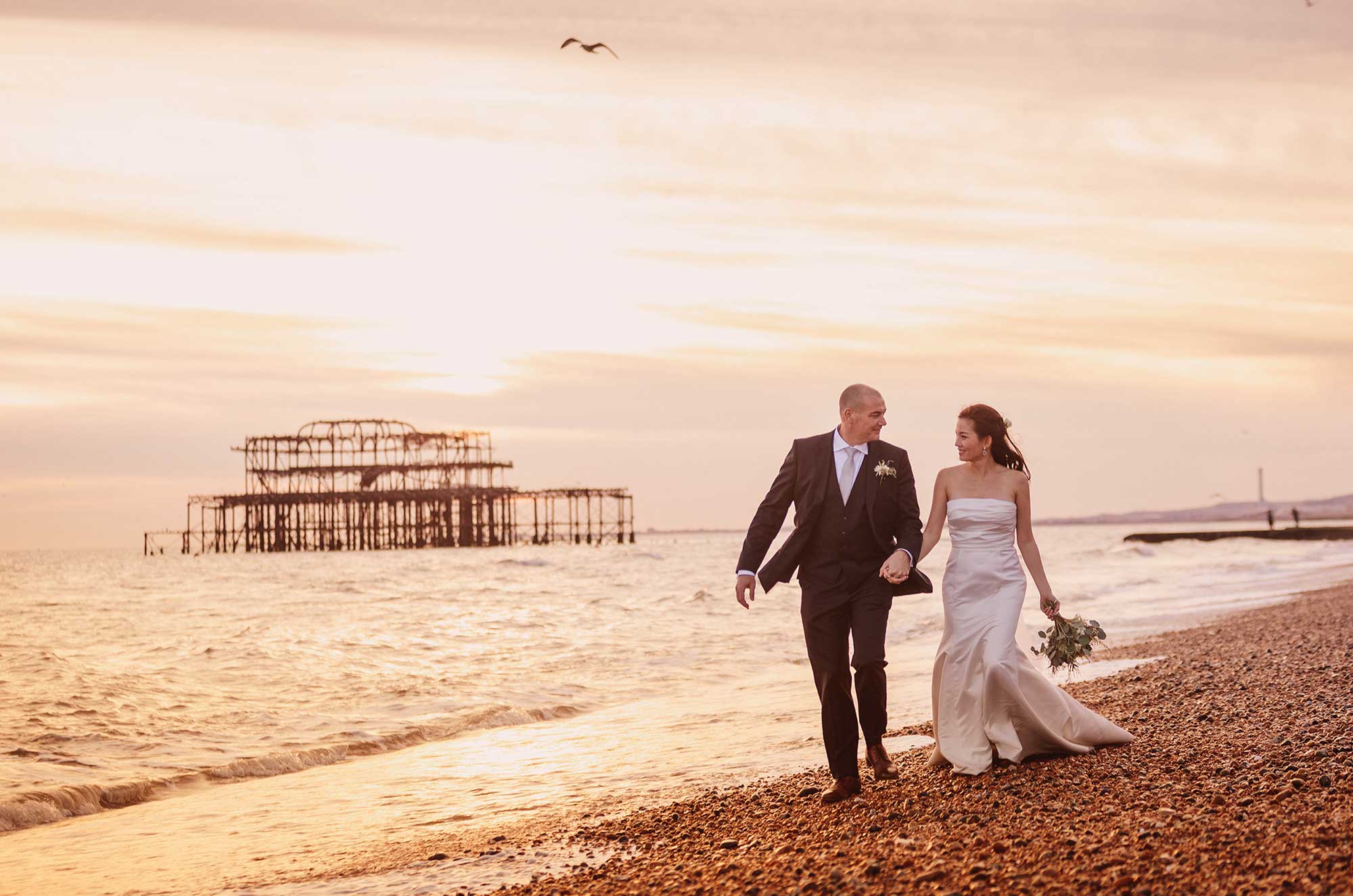 Bride and groom on Brighton beach in from of the West Pier