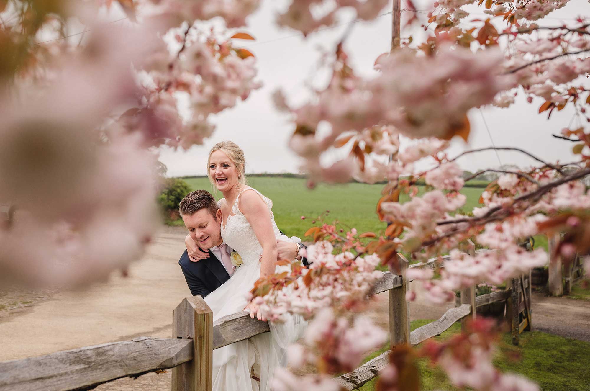 Groom lifting bride, shot through cherry blossom 