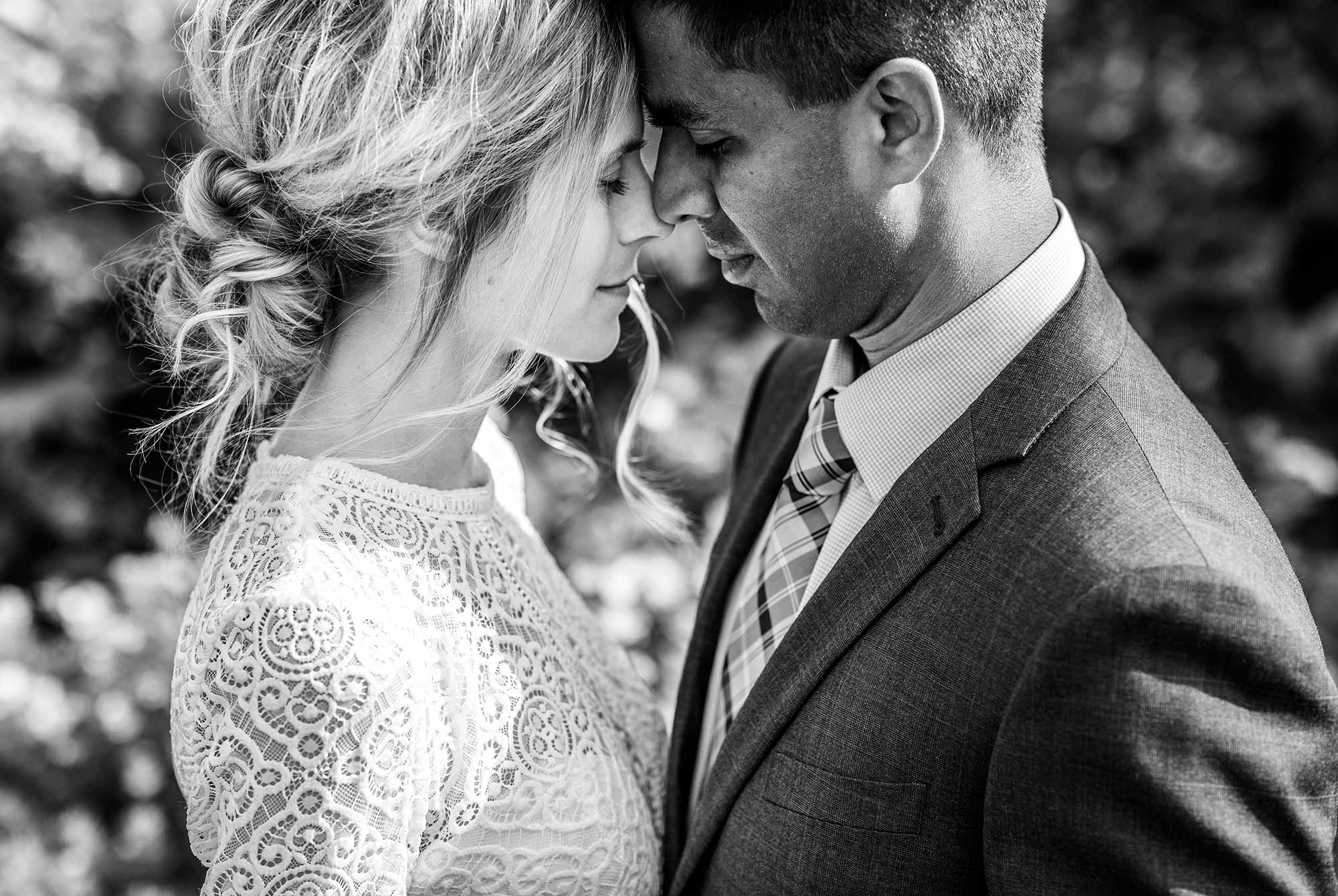 Bride and groom in close embrace, touching heads.