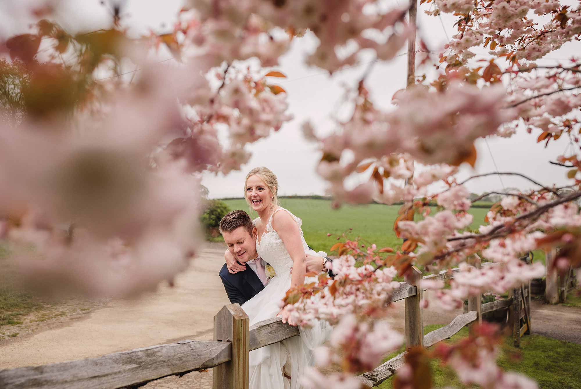 Groom lifts the bride in amongst the cherry blossom at their Bartholomew Barn wedding