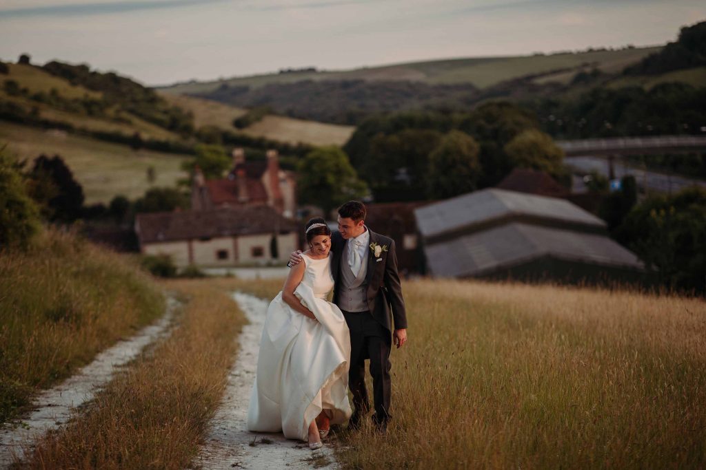 Bride and groom walking up the hill at Pangdean Barn at golden hour