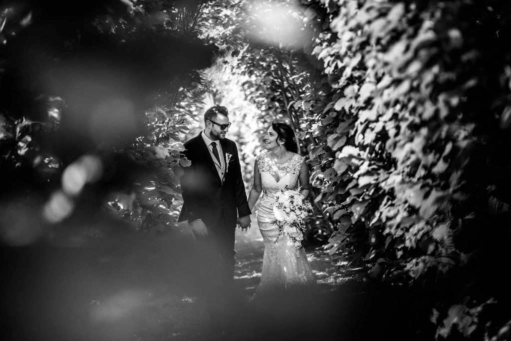 Bride and groom walk through the avenue of trees at Grittenham Barn