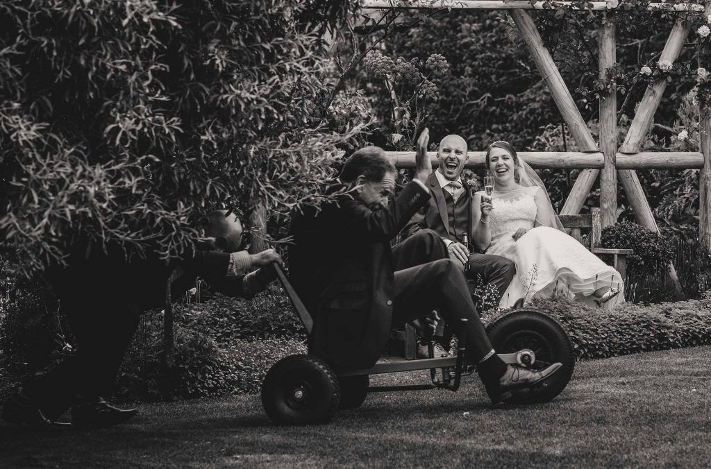 Bride and groom laughing as man on a trike goes past 