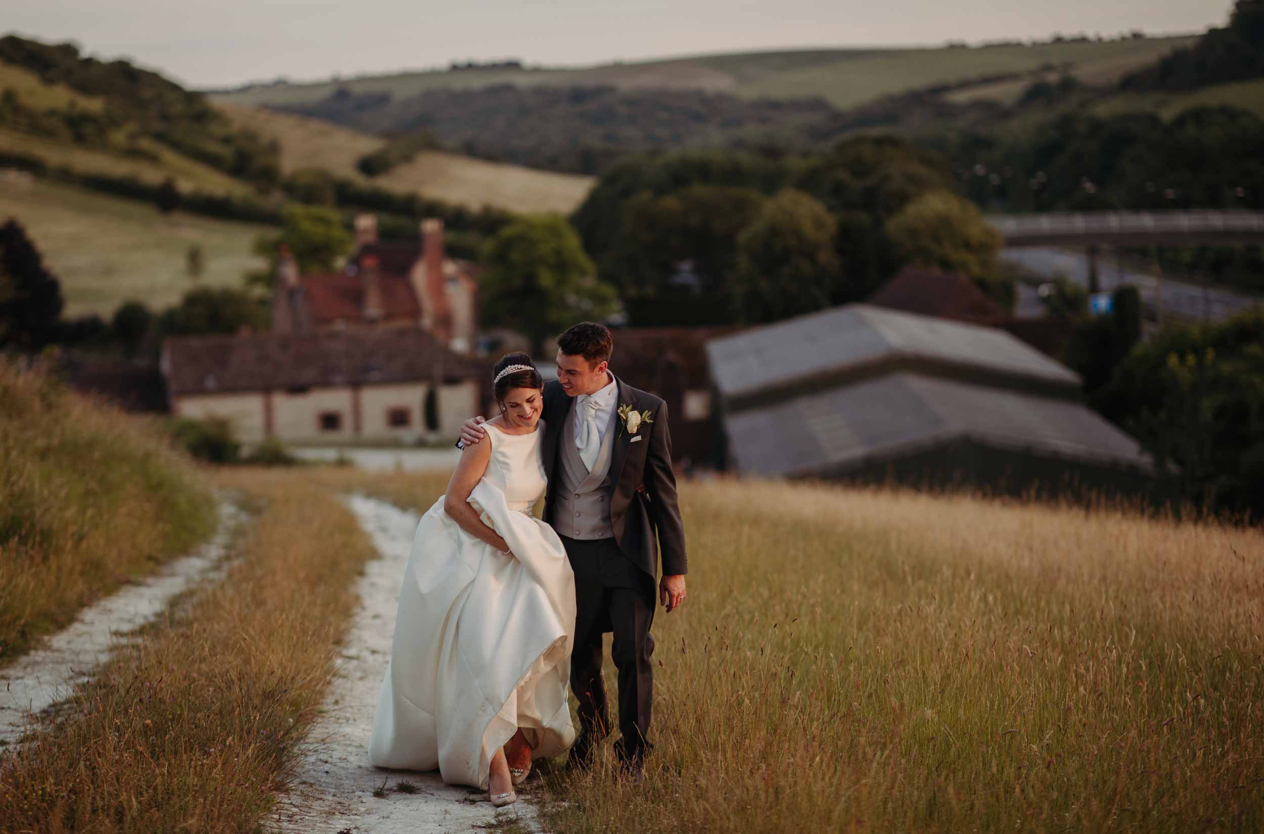 Bride and groom walking up a track at Pangdean Barn