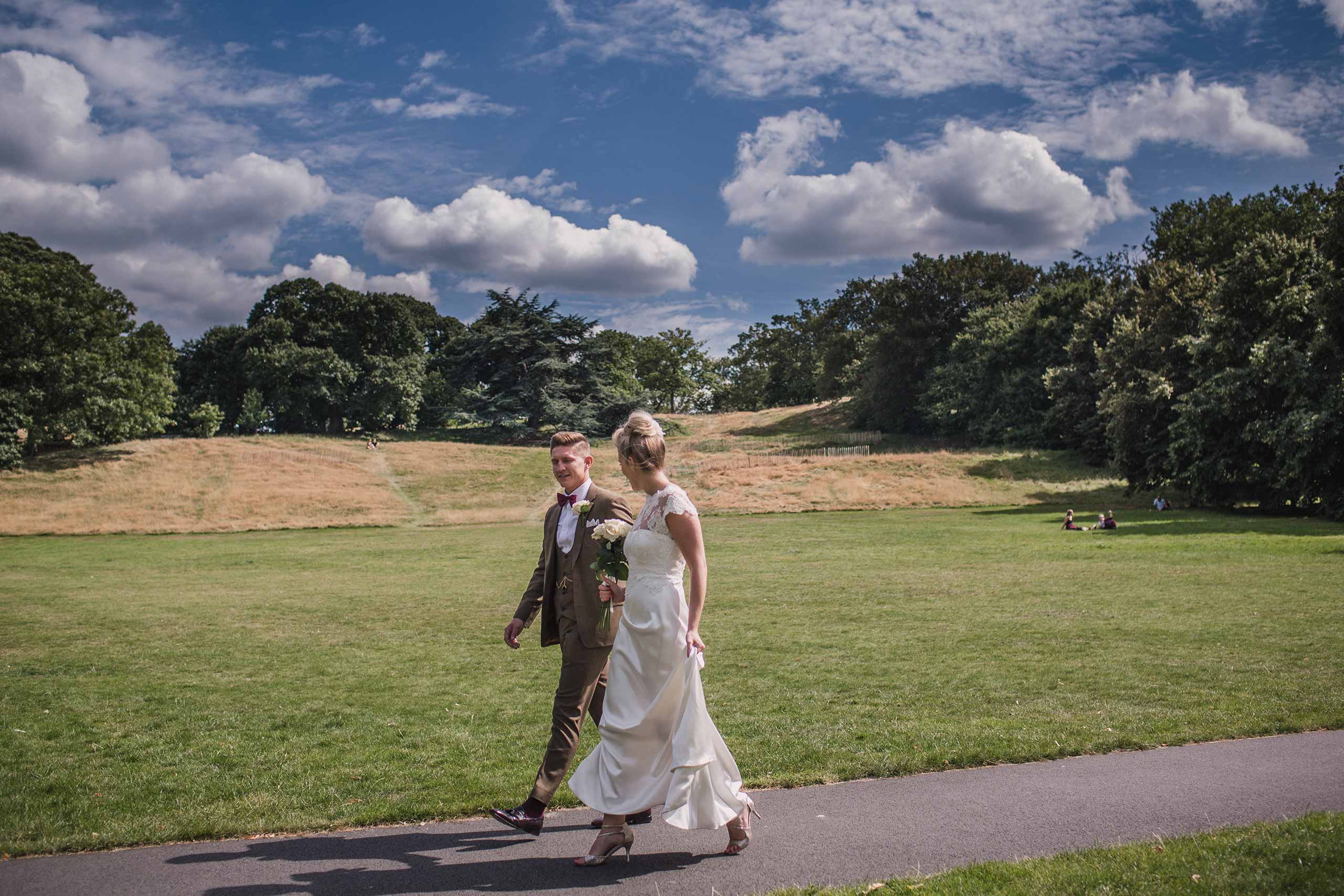 Bride and groom walking through Greenwich Park