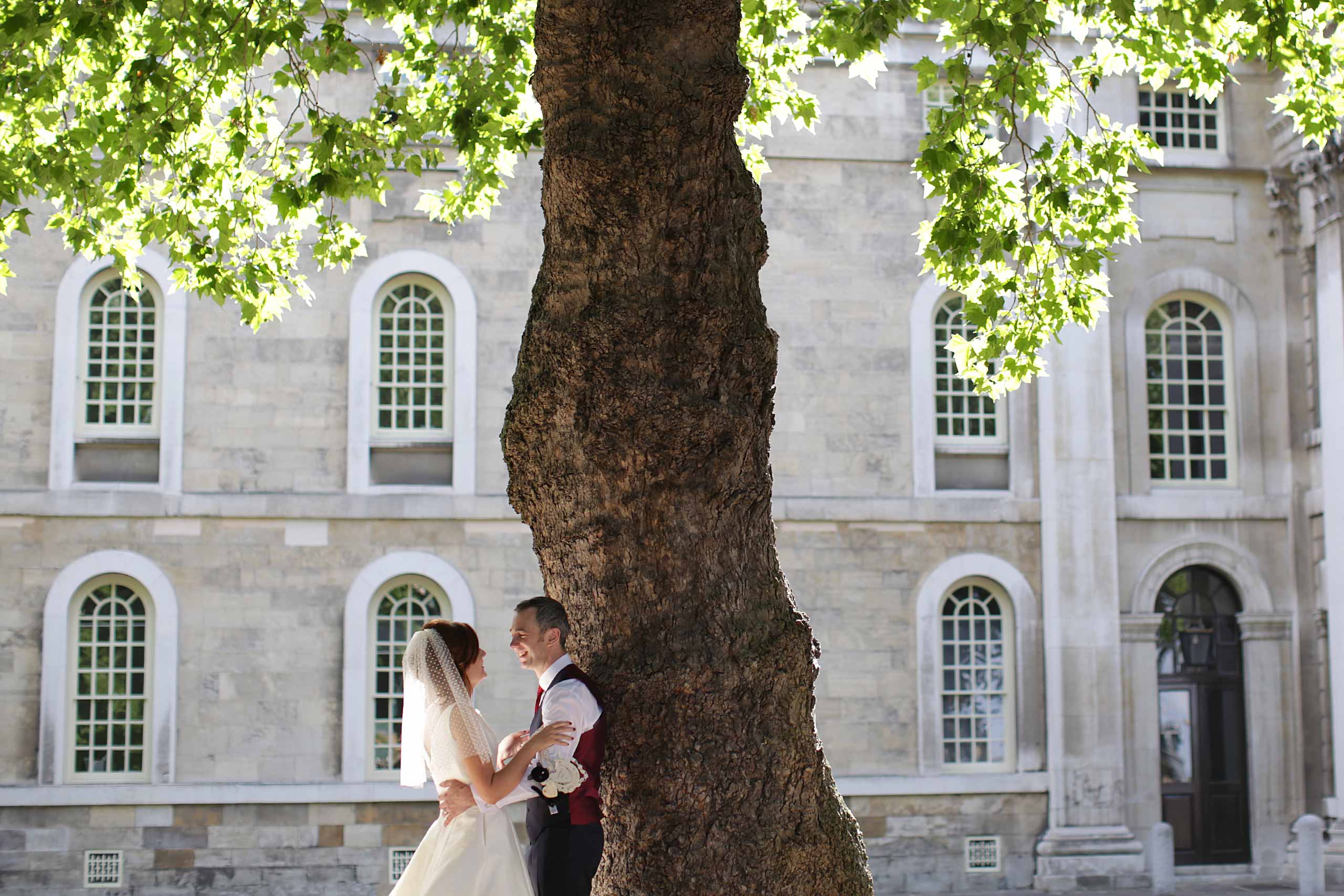 Bride and groom embracing under a beautiful sunlit tree in Greenwich