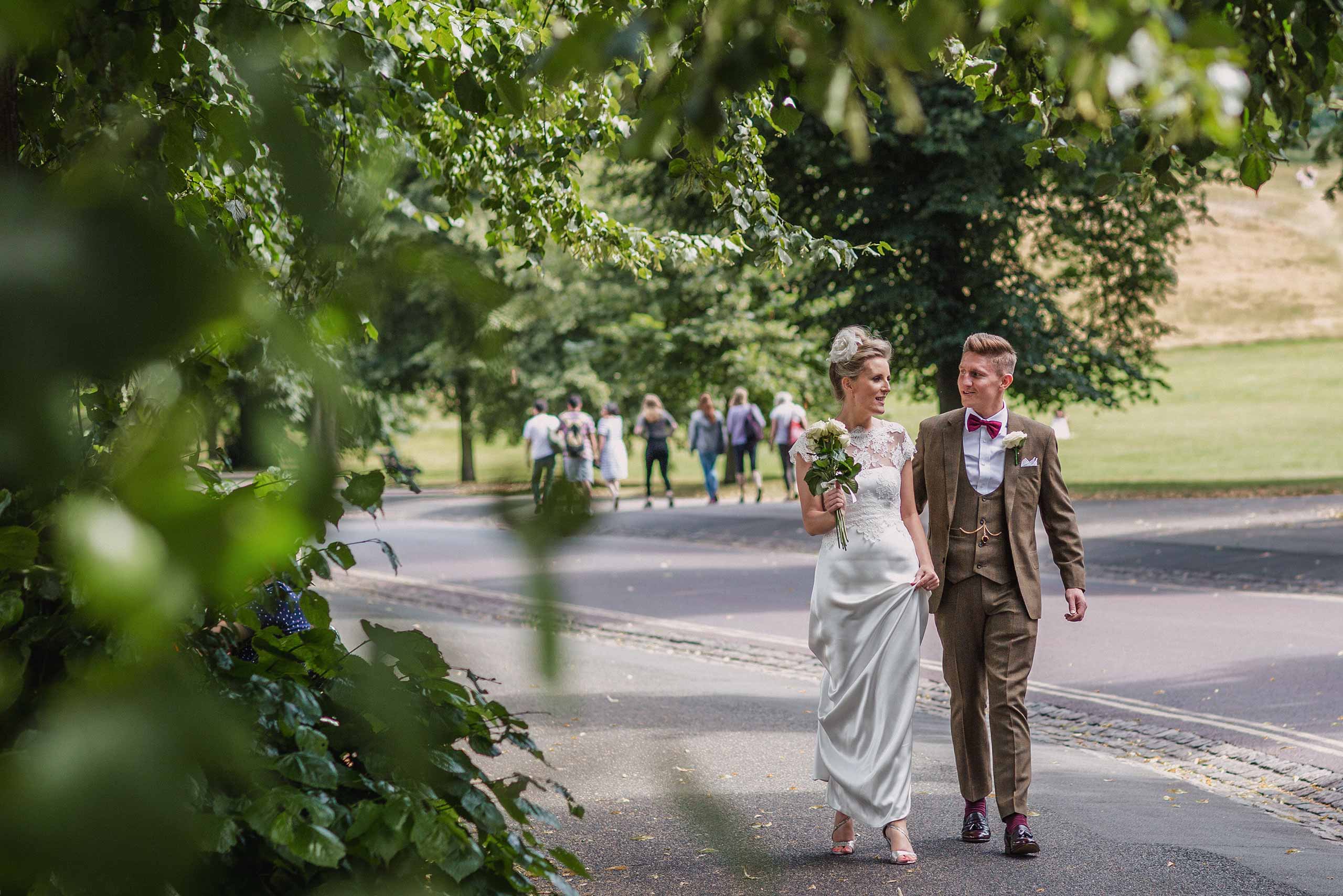 Bride and groom walking through Greenwich Park