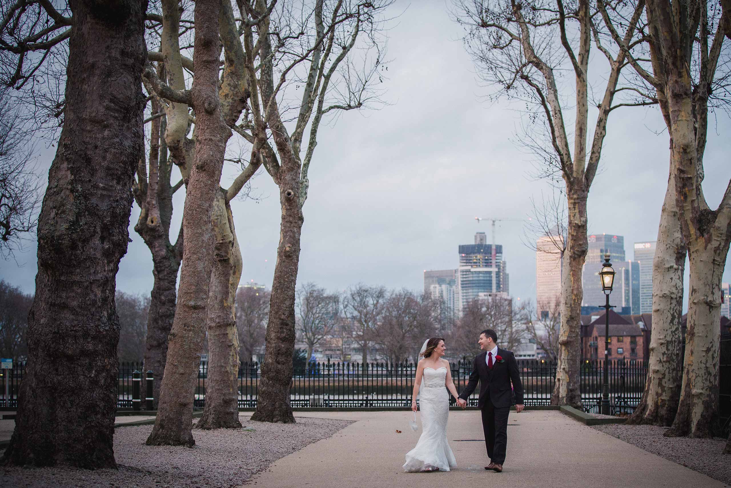 Bride and groom walking together against the London City backdrop in Greenwich