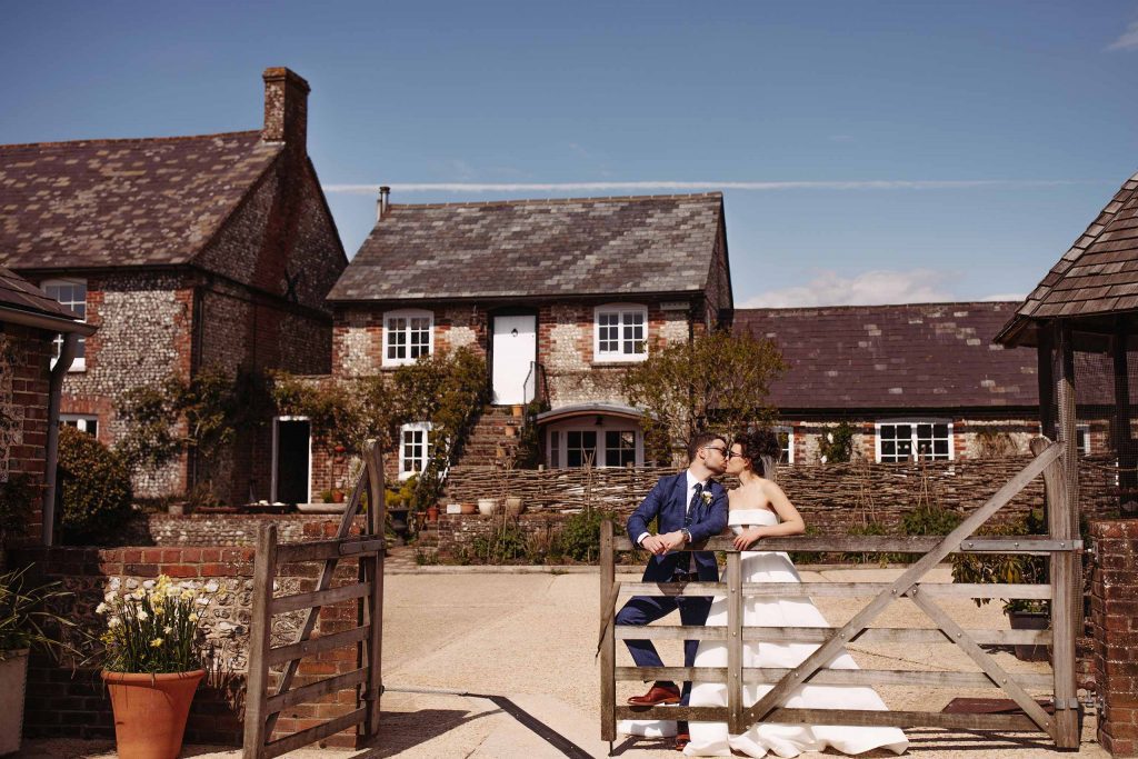 Bride and groom kiss at the gates of Upwaltham Barns cottage