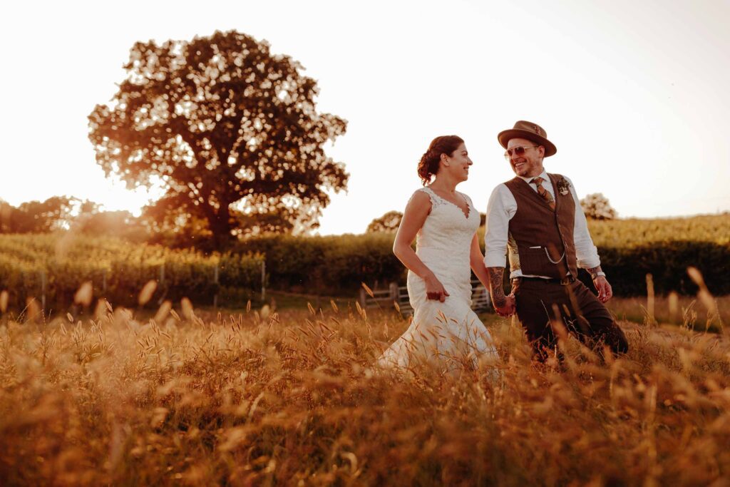 Bride and groom walking through a wheat field at golden hour 