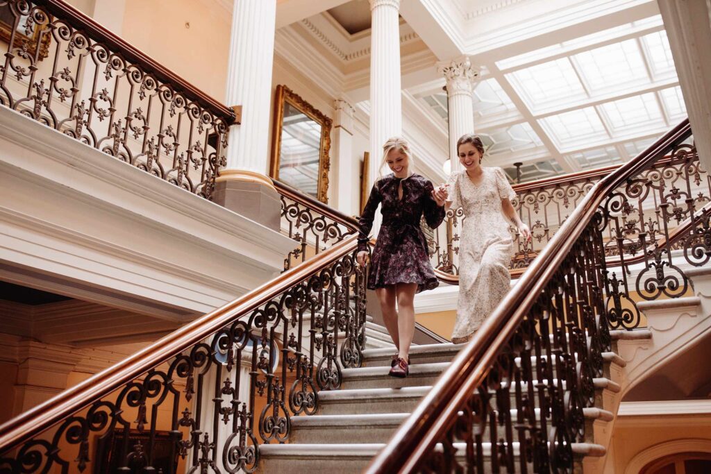 Two bride's walk down the staircase after their same sex Brighton Town Hall wedding ceremony