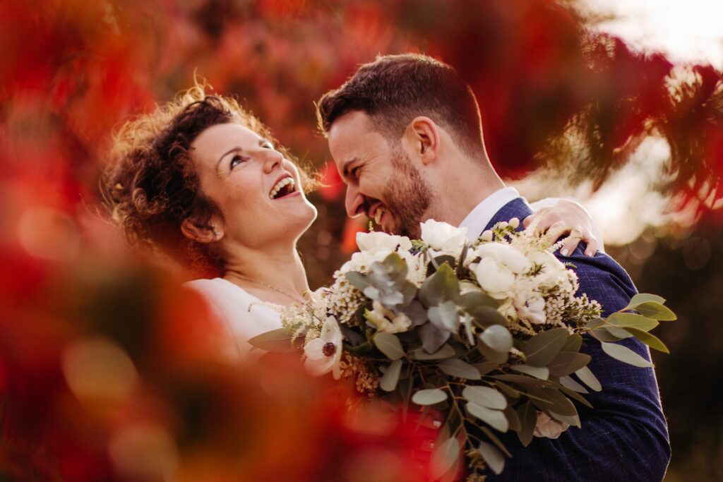 Bride and groom moment amongst a red tree at upwaltham barn