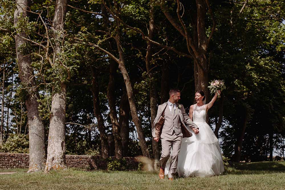 Bride cheering along with the groom as they come I’m outside of the trees