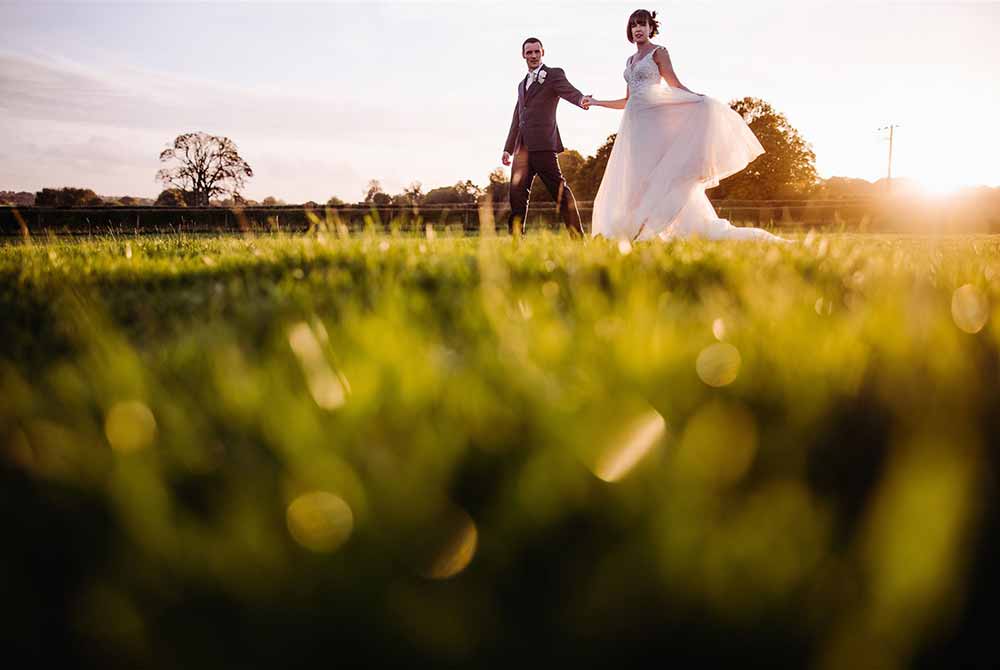 Bride and groom walk through the grass at Farbridge