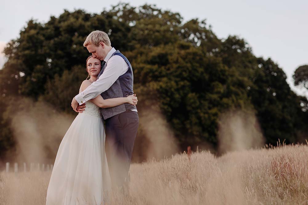 Bride and groom hug in the meadow at Hendall Manor Barn