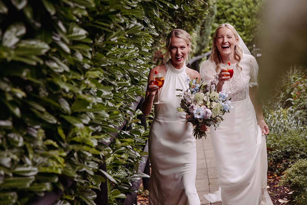 Two bride's walking and laughing at their same sex Pelham House wedding ceremony