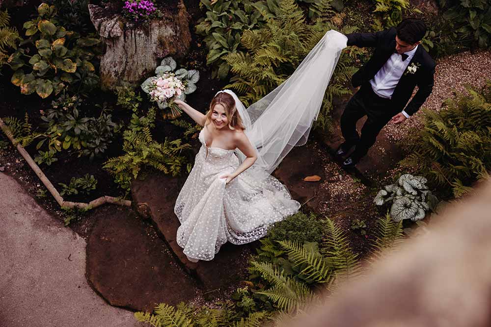 Bride and groom from above walking through the formal gardens at Hever Castle