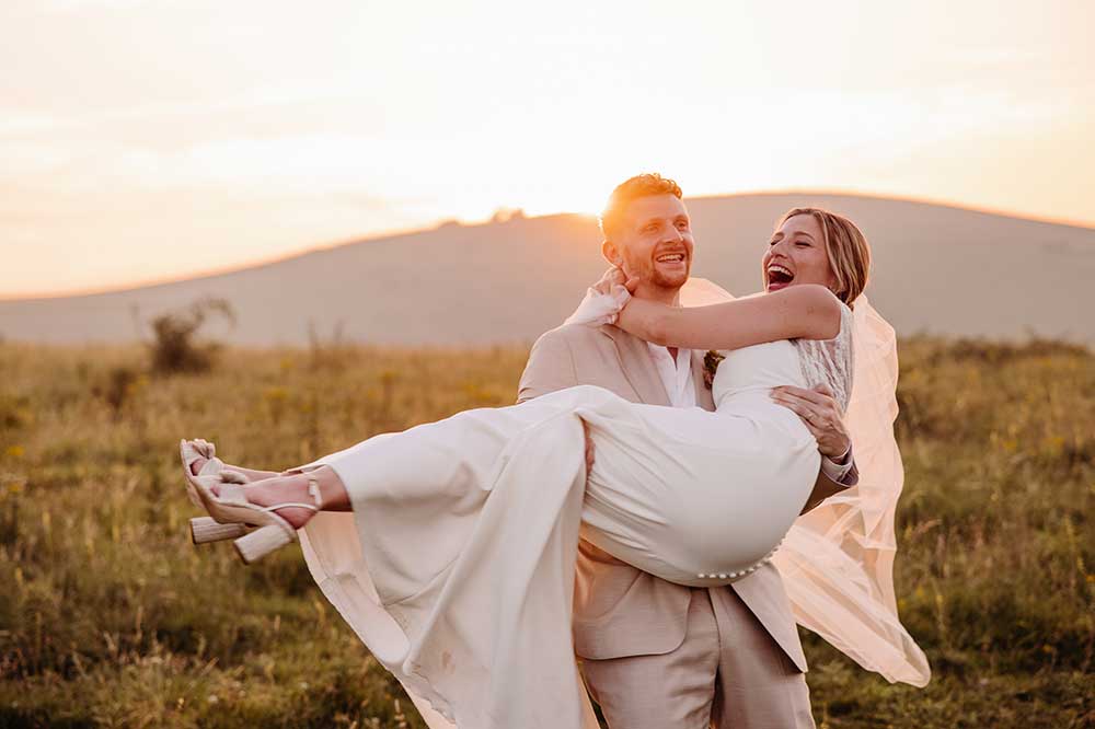 Groom lifting bride at golden hour on the South Downs
