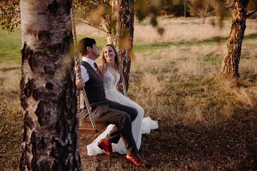 Golden hour bride and groom on the swing at Brookfield Barn